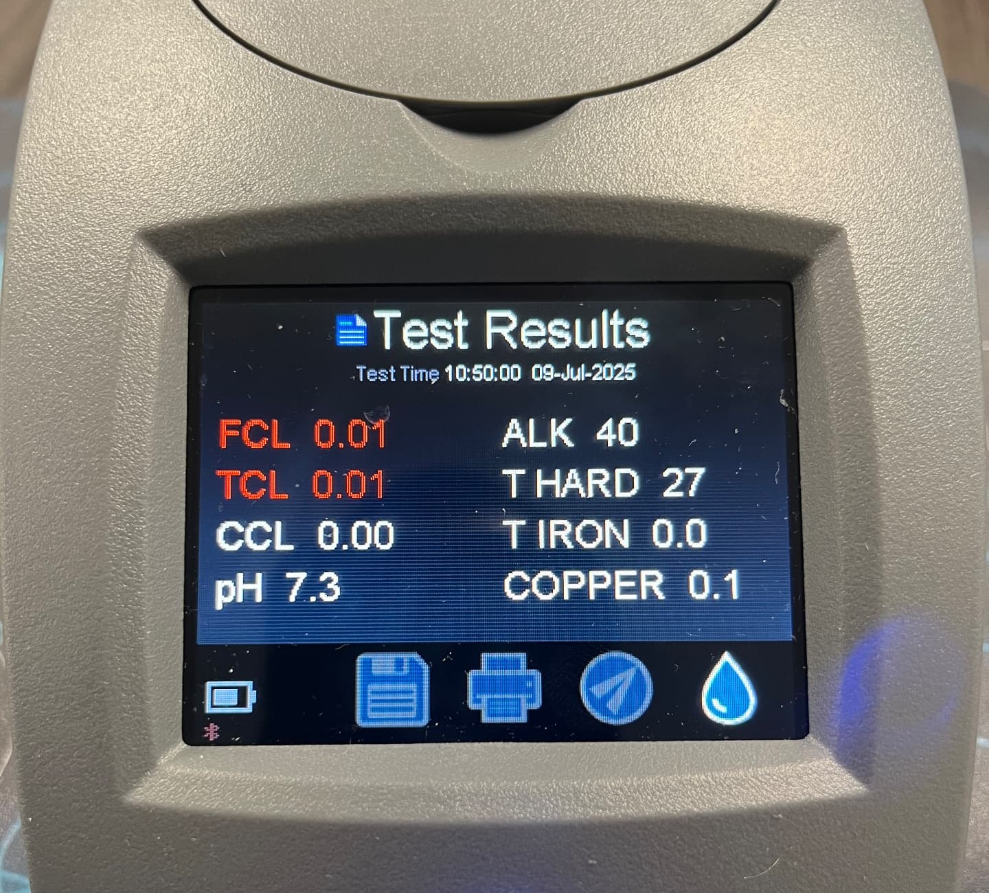Digital water test meter screen showing results for a sample: free chlorine 0.01, total chlorine 0.01, combined chlorine 0.00, pH 7.3, alkalinity 40, total hardness 27, total iron 0.0 and copper 0.1